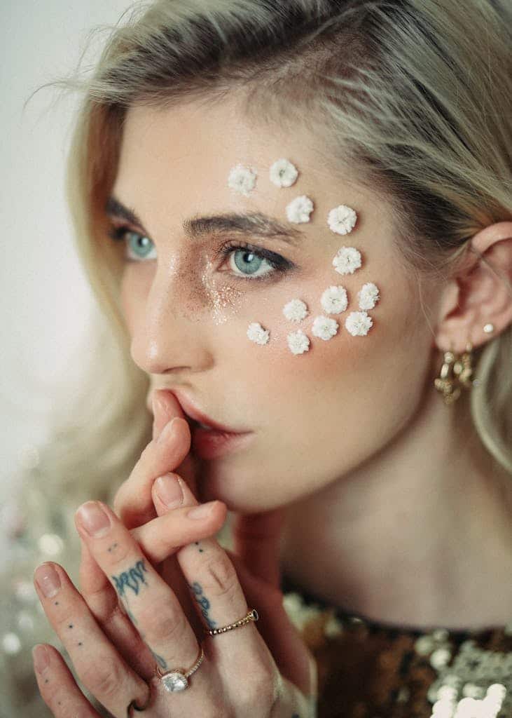 Stylish woman with floral accessories on face